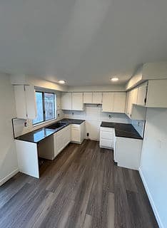 Modern kitchen with white cabinets, dark countertops, and ample natural light.
