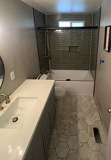 Modern bathroom design with gray tile, a bathtub, a shower, and a stylish vanity.