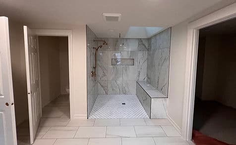 Modern bathroom design featuring a spacious walk-in shower with marble walls and a bench.